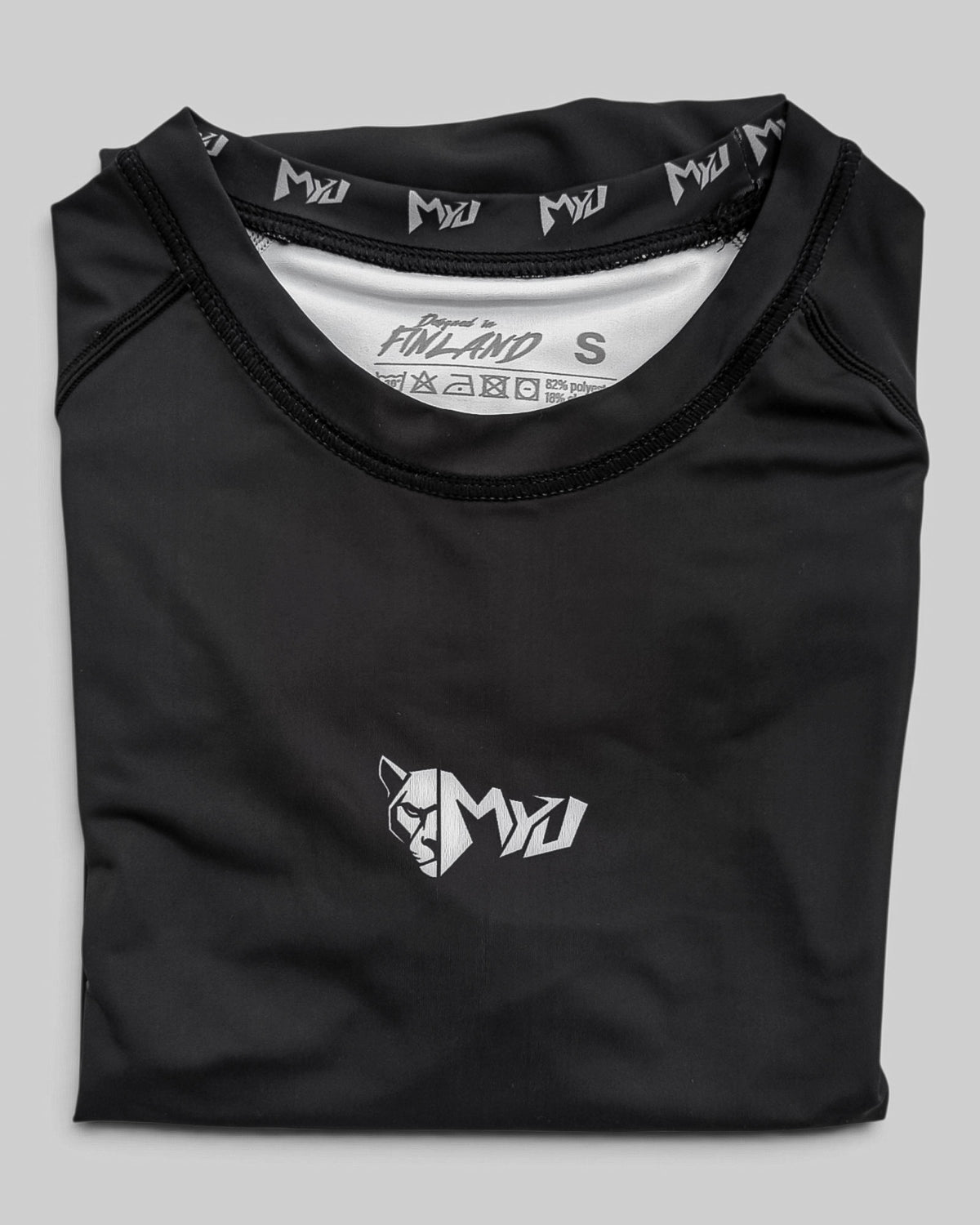 MYU Black rashguard, plain black short-sleeve no-gi BJJ compression top — folded front view